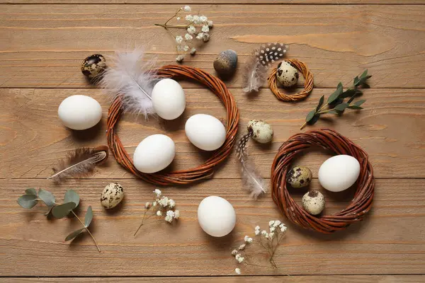 Tahta arka planda çelenkli, çiçekli ve tüylü Paskalya yumurtaları