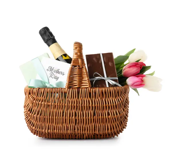 Beyaz arka planda Anneler Günü için şampanya şişesi, lale ve çikolata dolu sepet.