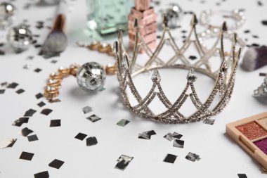 Mücevherleri, makyaj malzemeleri ve beyaz arka planda disko topları olan bir taç. Balo konsepti