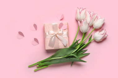 Hediye kutusu olan güzel lale çiçekleri ve pembe arka planda kağıt kalpler. Anneler Günü kutlaması