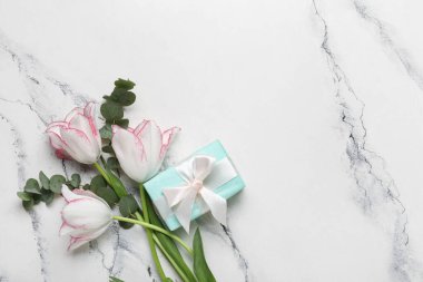 Okaliptüs dalları ve beyaz arka planda hediye kutusu olan güzel lale çiçekleri. Anneler Günü kutlaması
