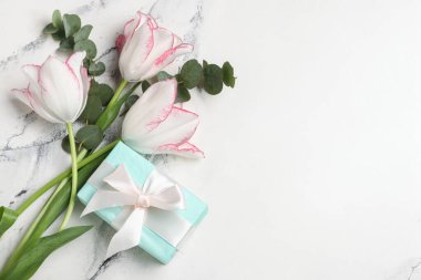 Okaliptüs dalları ve beyaz arka planda hediye kutusu olan güzel lale çiçekleri. Anneler Günü kutlaması