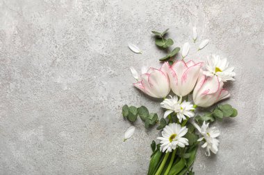 Papatya çiçekli güzel laleler ve gri arka planda okaliptüs dalları. Anneler Günü kutlaması