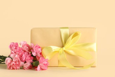 Güzel karanfil çiçekleri ve sarı arka planda hediye kutusu. Anneler Günü kutlaması