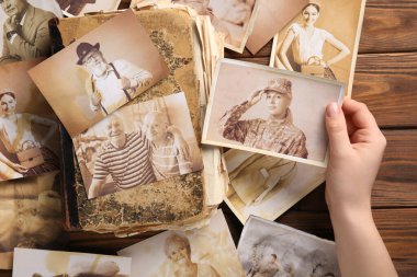 Eski albümleri ve tahta arka planda akrabalarının fotoğrafları olan bir kadın. Aile ağacı kavramı