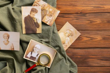 Ahşap zemin üzerinde büyüteç ve kumaş olan akrabaların eski fotoğrafları. Aile ağacı kavramı