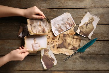 Ahşap arka planda akrabalarının eski fotoğrafları olan kadın elleri. Aile ağacı kavramı