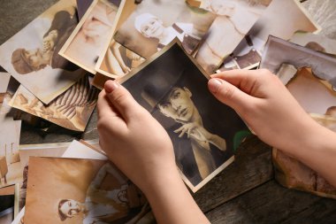 Ahşap arka planda akrabalarının eski fotoğrafları olan kadın elleri. Aile ağacı kavramı