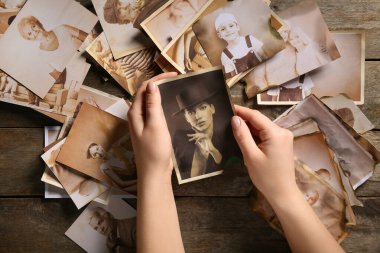 Ahşap arka planda akrabalarının eski fotoğrafları olan kadın elleri. Aile ağacı kavramı