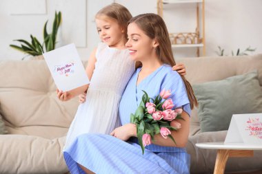 Anneler Günü 'nde annesini laleler ve kartpostalla selamlayan tatlı küçük bir kız.