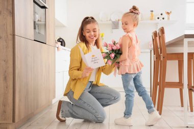 Anneler Günü 'nde annesini laleler ve kartpostalla selamlayan tatlı küçük bir kız.