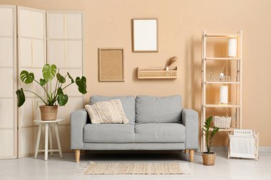 Oturma odasında çiçek, ahşap askı ve lambalar olan gri kanepe.