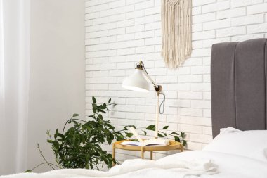 Işık odasındaki yatağın yanındaki masada parlayan lamba ve kitap