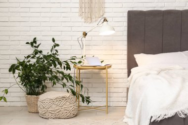 Masada parlayan lamba, çiçekli ve ışık odasında yatağın yanında puf.