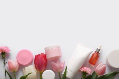 Farklı kozmetik ürünleri ve açık arkaplanda güzel çiçekler