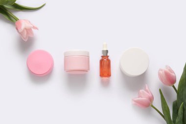 Farklı kozmetik ürünleri ve açık arkaplanda güzel çiçekler