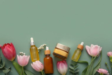 Farklı kozmetik ürünleri ve yeşil arka planda güzel çiçekler.