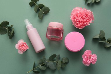 Farklı kozmetik ürünleri ve yeşil arka planda güzel çiçekler.
