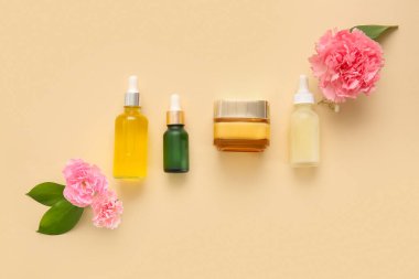 Bej arka planda farklı kozmetik ürünleri ve güzel çiçekler