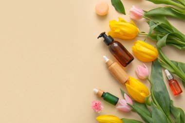 Bej arka planda farklı kozmetik ürünleri ve güzel çiçekler