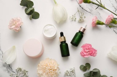 Farklı kozmetik ürünleri ve açık arkaplanda güzel çiçekler