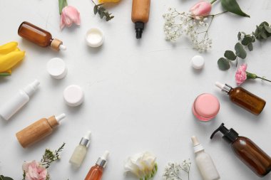 Farklı kozmetik ürünlerinden yapılmış çerçeve ve hafif arkaplanda güzel çiçekler
