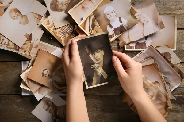 Ahşap arka planda akrabalarının eski fotoğrafları olan kadın elleri. Aile ağacı kavramı