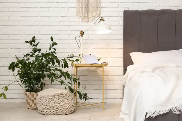 Masada parlayan lamba, çiçekli ve ışık odasında yatağın yanında puf.