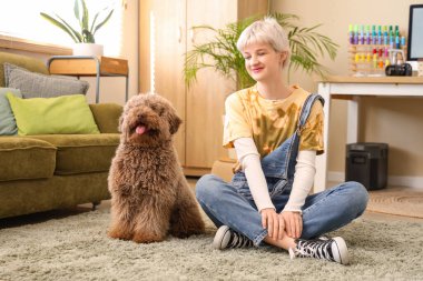 Genç bir kadın iş yerinin yanındaki açık ofiste fino köpeğiyle yerde oturuyor.