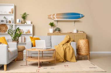 Laptop sehpası ve sörf tahtasıyla modern oturma odasının içinde.