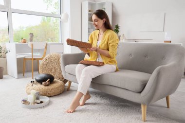 Sadhu tahtasıyla evdeki kanepede oturan genç kadın.