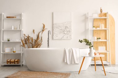 Banyonun içinde raf üniteleri, küvet ve yapay bitkiler var.