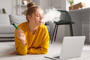 Evde tek kullanımlık elektronik sigara içen genç bir kadın.