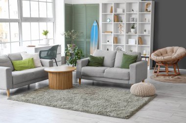 Interior of stylish modern living room with surfboard and sofas