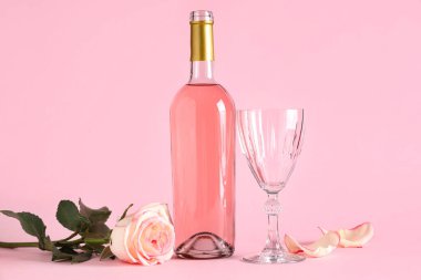 Bir şişe pembe şarap ve arka planda güzel bir gül ve cam.
