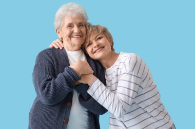 Annesi mavi arka planda sarılan olgun bir kadın.