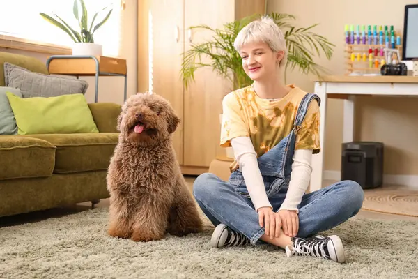 Genç bir kadın iş yerinin yanındaki açık ofiste fino köpeğiyle yerde oturuyor.