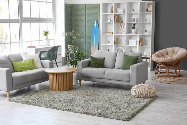 Interior of stylish modern living room with surfboard and sofas