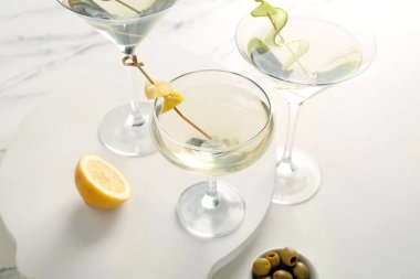 Beyaz masada bir bardak lezzetli martini ve limon.