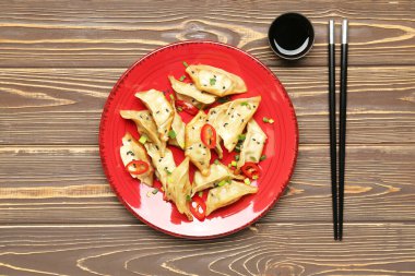 Lezzetli Çin jiaozi tabağı, susam ve ahşap arka planda yeşil soğan.