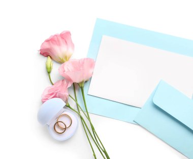 Zarflı kompozisyon, boş kartlar, östoma çiçekleri ve beyaz arkaplanda alyanslar.