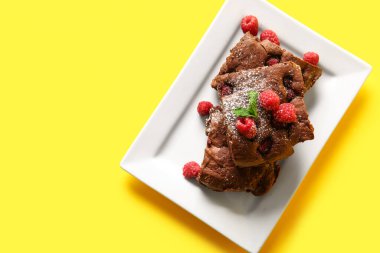 Sarı arka planda ahududulu çikolatalı browni tabağı.
