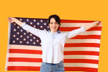 Sarı arka planda ABD bayrağı olan güzel genç bir kadın.