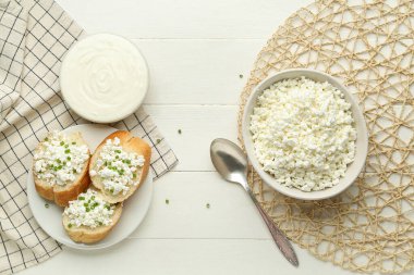 Süzme peynirli ekmek parçaları ve beyaz ahşap masada ekşi krema.