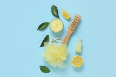 Bir kase limonlu vücut fırçası ve mavi arka planda banyo malzemeleri.