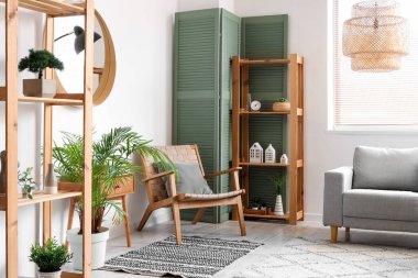 Rahat koltuk, kanepe, raf ünitesi ve oturma odasındaki katlanabilir ekran.