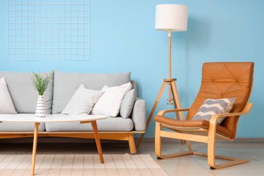 Rahat koltuk, kanepe ve mavi duvarın yanındaki masa.