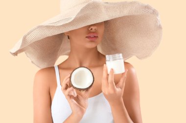 Şapkalı ve bej arka planda hindistan cevizi yağı olan güzel bir kadın.