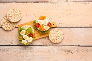 Bıldırcın yumurtalı pirinç krakerleri, domatesler ve hafif ahşap arka planda marul.