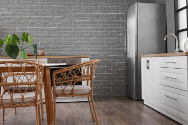 Modern mutfak, yemek masası, buzdolabı ve beyaz tezgahlar.